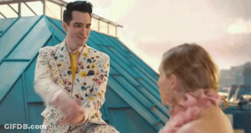 Man In Floral Suit Shaking Hands With Woman In Pink GIF