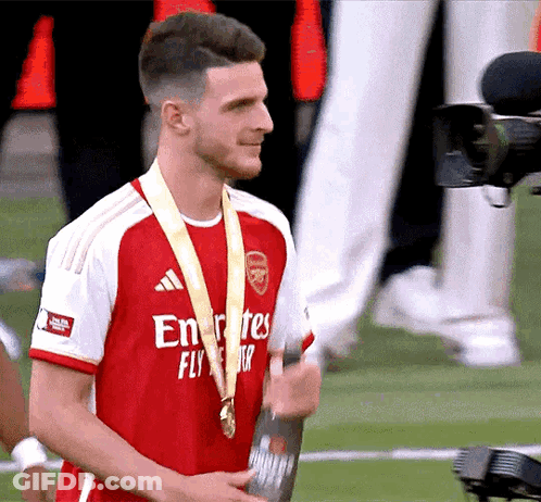 Man In Fly Emirates Jersey Holding Medal GIF