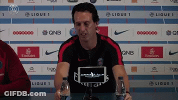 Man In Fly Emirates Shirt At Table With Water Bottles GIF