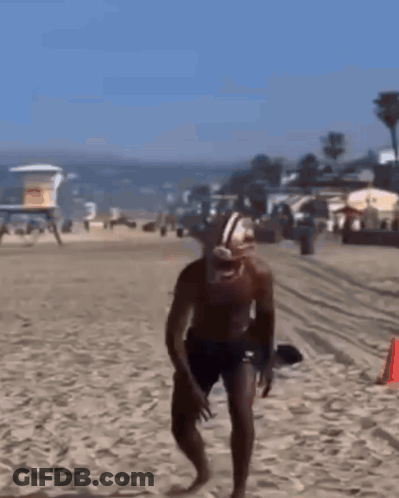 Man In Football Helmet And Shorts Running On Beach GIF