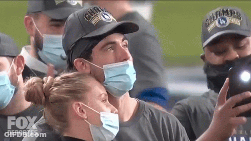 Man In Fox Deportes Hat Taking Selfie With Masked Woman GIF