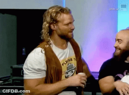 Man In Fringed Vest And Pledge T-Shirt With Another Man GIF