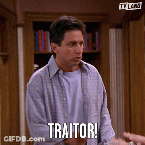 Man In Front Of Bookshelf Says Traitor GIF