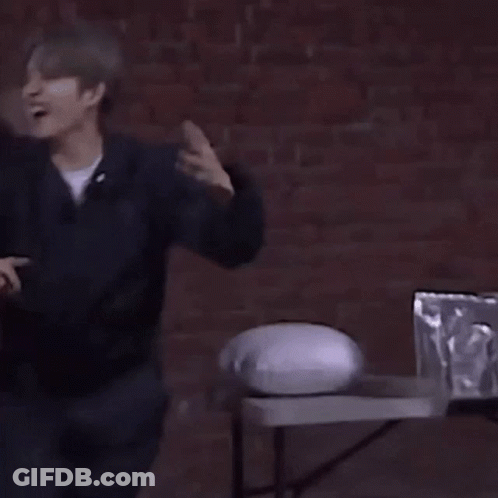 Man In Front Of Brick Wall With Table And Pillow GIF