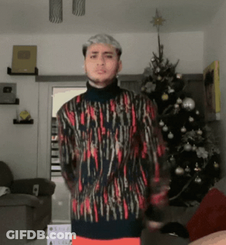 Man In Front Of Christmas Tree Wearing Sweater GIF