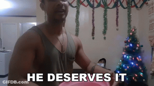 Man In Front Of Christmas Tree With He Deserves It GIF