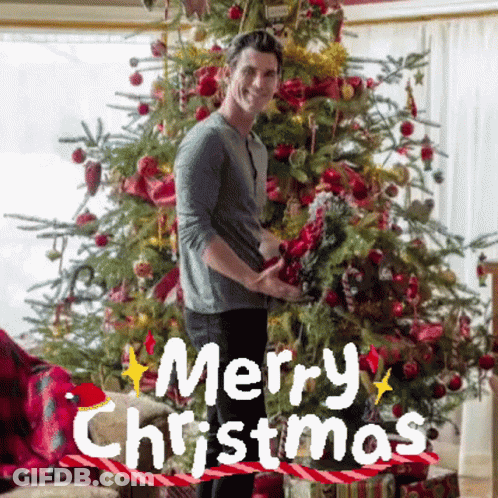 Man In Front Of Christmas Tree With Merry Christmas GIF