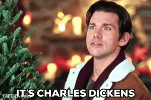Man In Front Of Christmas Tree With Words It's Charles Dickens GIF