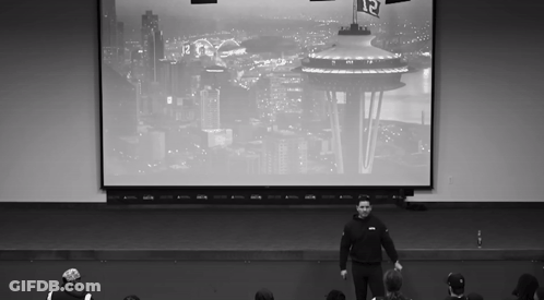 Man In Front Of Seattle Screen With Number 12 GIF