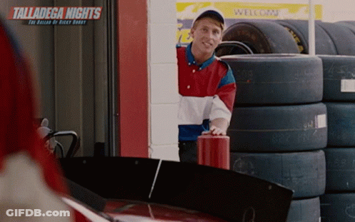 Man In Front Of Talladega Nights Sign And Tires GIF