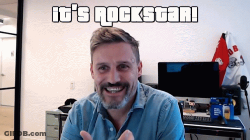 Man In Front Of Wall Saying It's Rockstar GIF