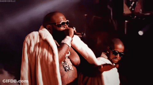 Man In Fur Coat Singing, Another Man Looking On GIF