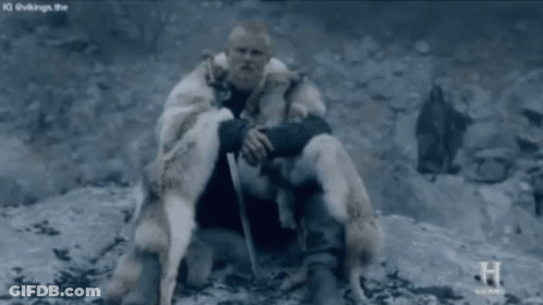 Man In Fur Coat Sitting On Rock Holding Sword GIF