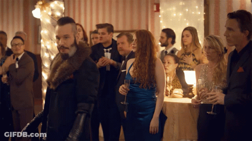 Man In Fur Coat Standing In Crowd GIF