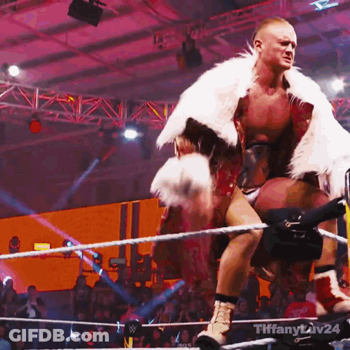Man In Fur Coat Standing In Wrestling Ring With Tiffany Liv24 GIF