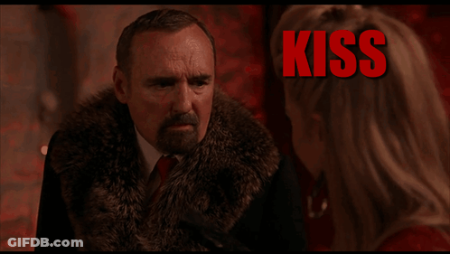 Man In Fur Coat Talking To Woman With Kiss Behind Him GIF