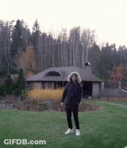 Man In Fur Hooded Jacket In Front Of House GIF