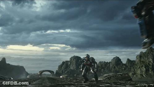 Man In Futuristic Suit Walking Across Bridge With Mountains GIF
