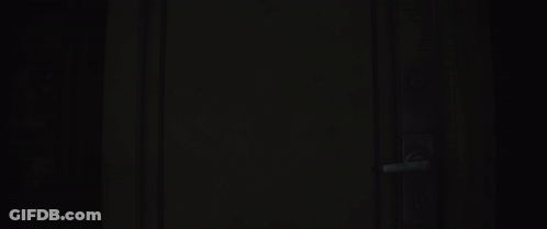 Man In Gas Mask With Yellow Eyes Standing In Dark Hallway GIF