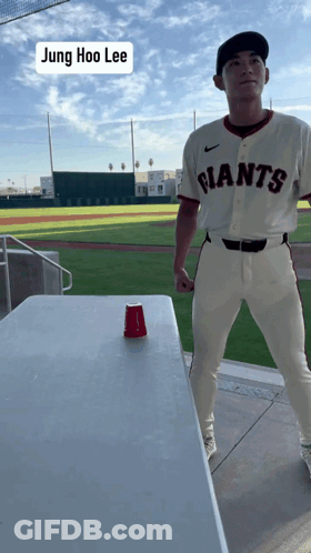 Man In Giants Jersey Standing By Table GIF