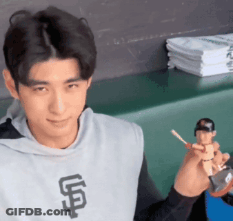 Man In Giants Shirt Holding Baseball Figurine GIF