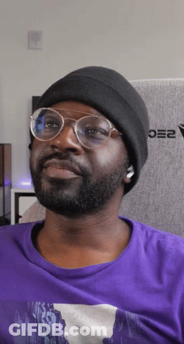 Man In Glasses And Black Beanie Sitting In Front Of Oe2 Wall GIF