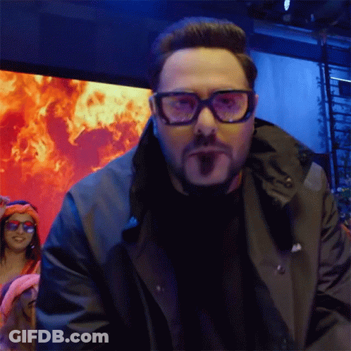 Man In Glasses And Black Jacket Facing Flames GIF