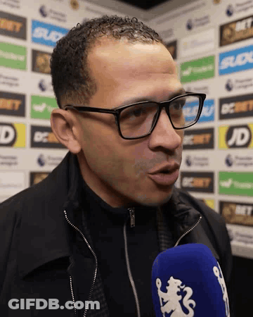 Man In Glasses And Black Jacket Talking Into Blue Microphone GIF