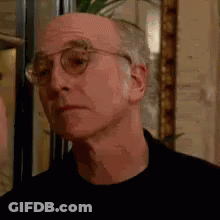 Man In Glasses And Black Shirt Looking At Camera GIF