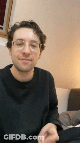 Man In Glasses And Black Shirt On Bed GIF