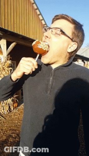 Man In Glasses And Black Sweater Eating Caramel Apple GIF