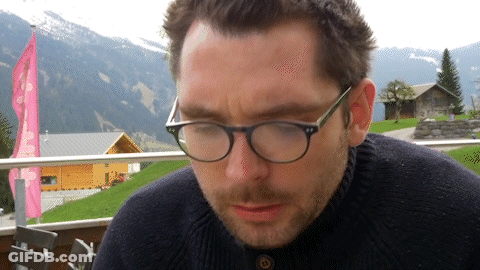 Man In Glasses And Black Sweater Looking Down GIF