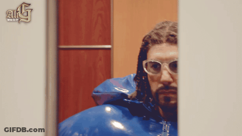 Man In Glasses And Blue Jacket In Front Of A & G Wall GIF