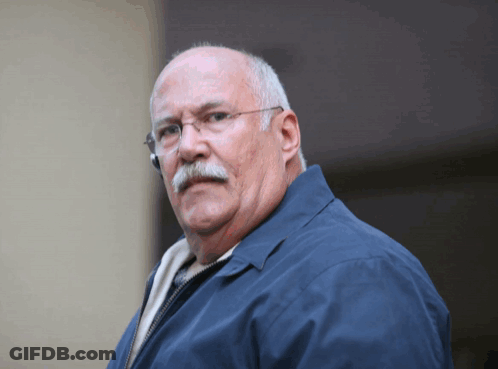 Man In Glasses And Blue Jacket Looking At Camera GIF
