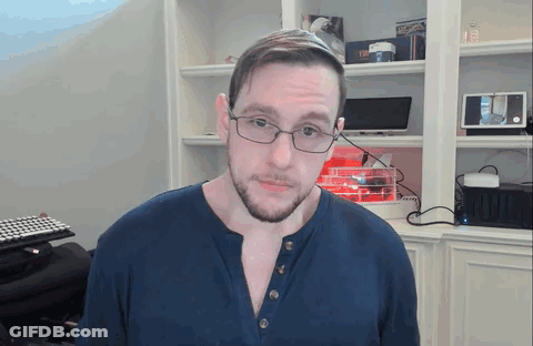 Man In Glasses And Blue Shirt In Front Of Bookcase GIF