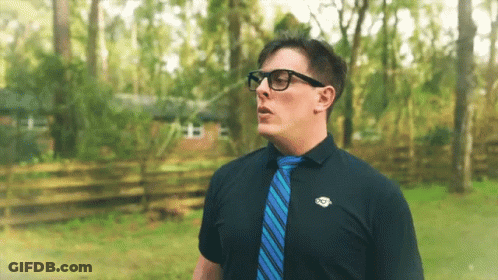 Man In Glasses And Blue Tie In Front Of House GIF