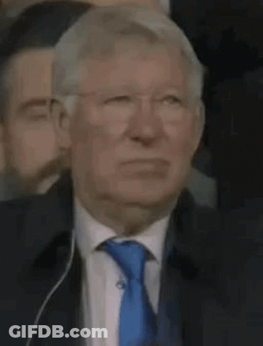 Man In Glasses And Blue Tie Sitting In Crowd GIF