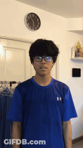 Man In Glasses And Blue Under Armour Shirt Beside Clock GIF