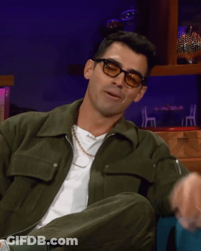 Man In Glasses And Green Jacket Sitting Down GIF