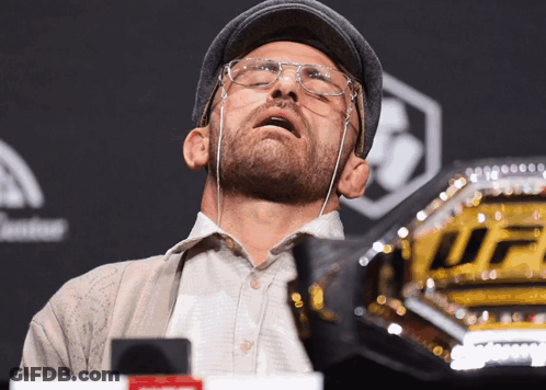 Man In Glasses And Hat Looking Up At UFC Belt GIF