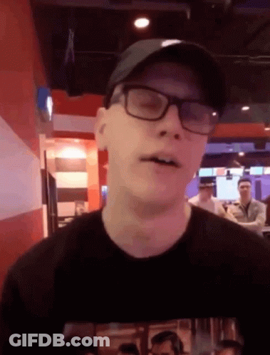 Man In Glasses And Hat Looks At Camera GIF