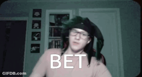Man In Glasses And Hat Standing Before Bet Wall GIF