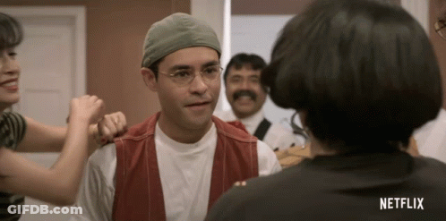 Man In Glasses And Hat Talking To Woman With Netflix Shirt GIF