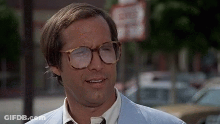 Man In Glasses And Light Blue Suit In Front Of No Parking Sign GIF