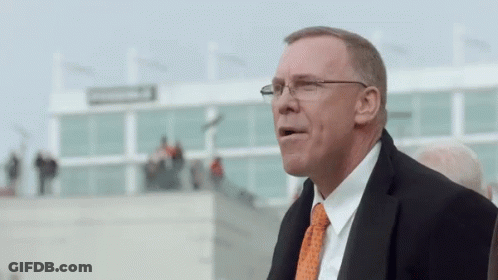 Man In Glasses And Orange Tie At Large Building GIF