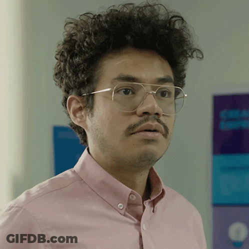 Man In Glasses And Pink Shirt In Front Of Blue And Purple Sign GIF