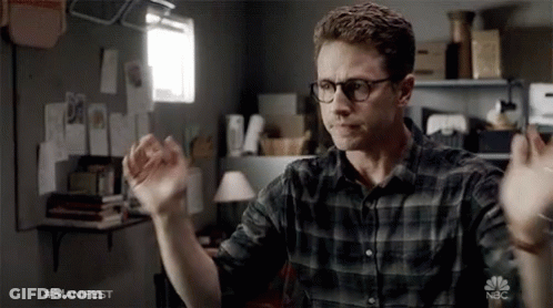 Man In Glasses And Plaid Shirt In Front Of NBC Logo GIF