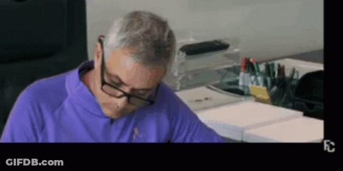 Man In Glasses And Purple Shirt Sitting At Table GIF