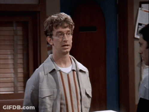 Man In Glasses And Striped Shirt In Front Of Door GIF