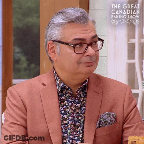 Man In Glasses And Suit In Front Of Great Canadian Baking Show Sign GIF